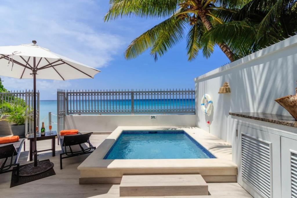 einen Pool mit einem Tisch und einem Sonnenschirm in der Unterkunft Westshore Beach House by Blue Sky Luxury in Saint James
