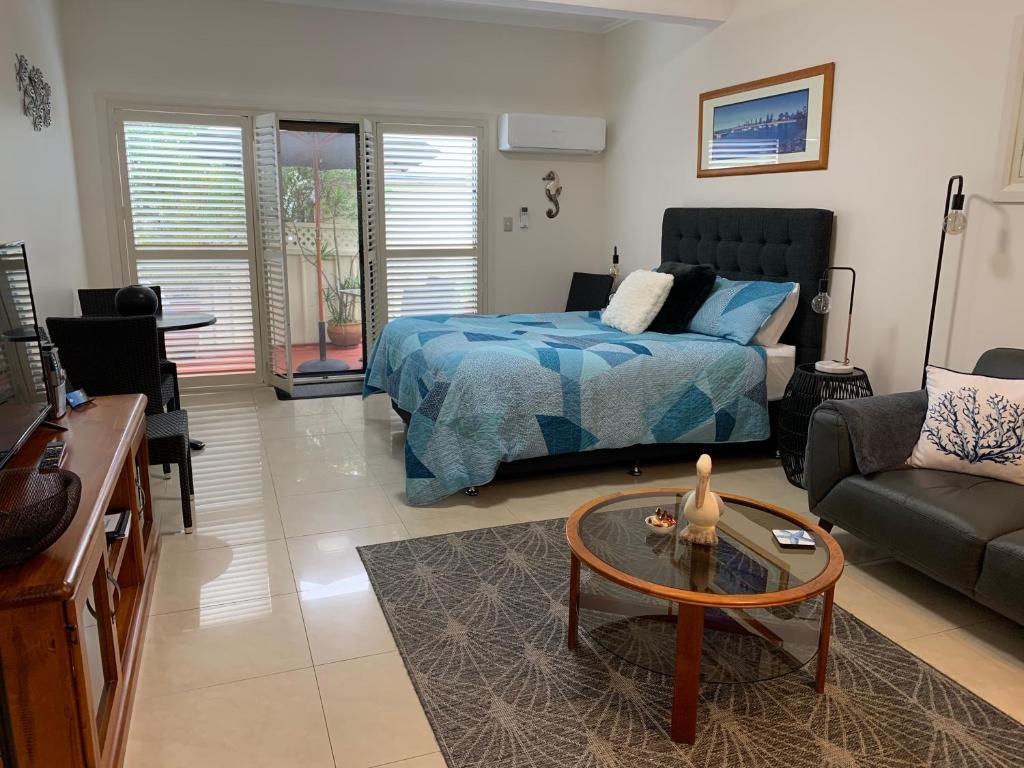 a bedroom with a bed and a couch and a table at Pelicans Rest Shellharbour in Shellharbour