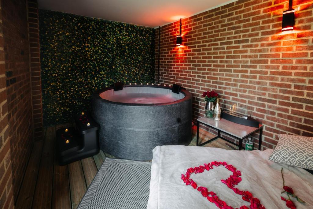 um quarto com uma banheira numa parede de tijolos em Casa Amor - Kinky Hotel UK em Southampton