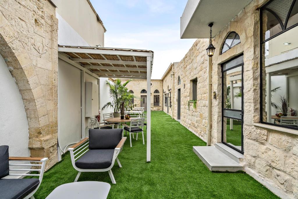 an outdoor patio with green grass and chairs at Old City Boutique - בוטיק העתיקה מבית רשת מלונות לה פינקה in Beer Sheva
