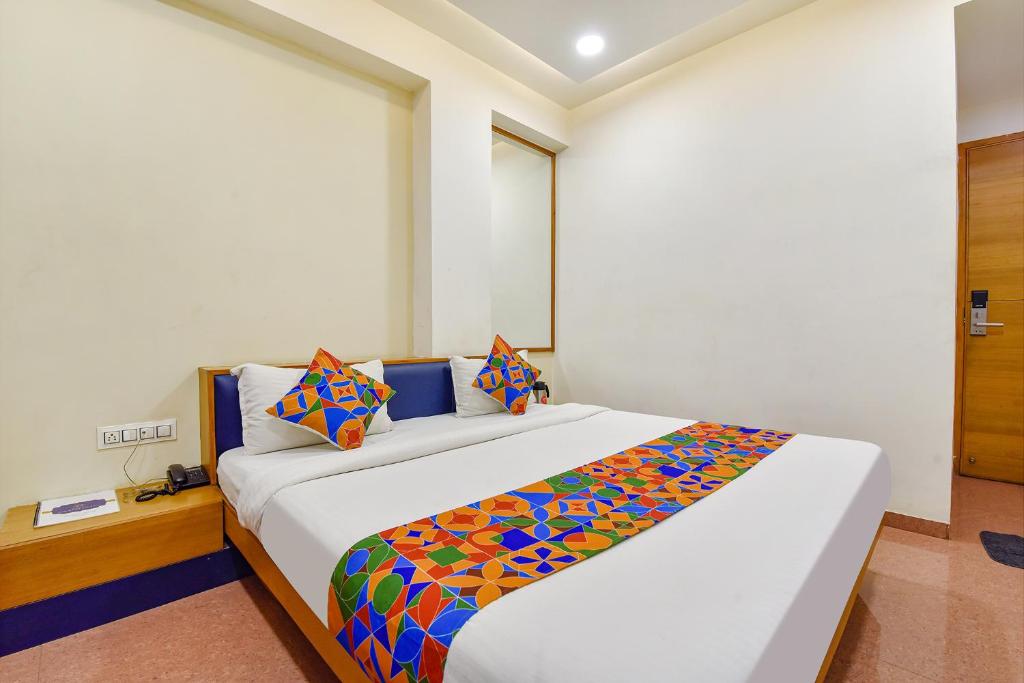 a bedroom with a large white bed with colorful sheets at FabHotel Prime Grand Unity, Changodar in Ahmedabad