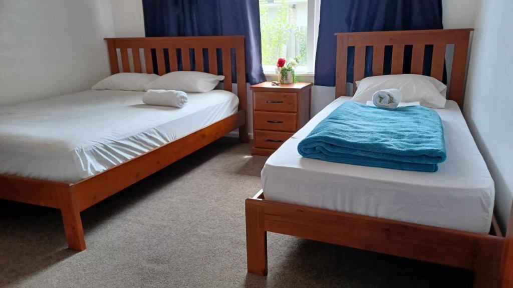 two twin beds in a bedroom with blue curtains at Homestay Triple room, near the city center in Christchurch