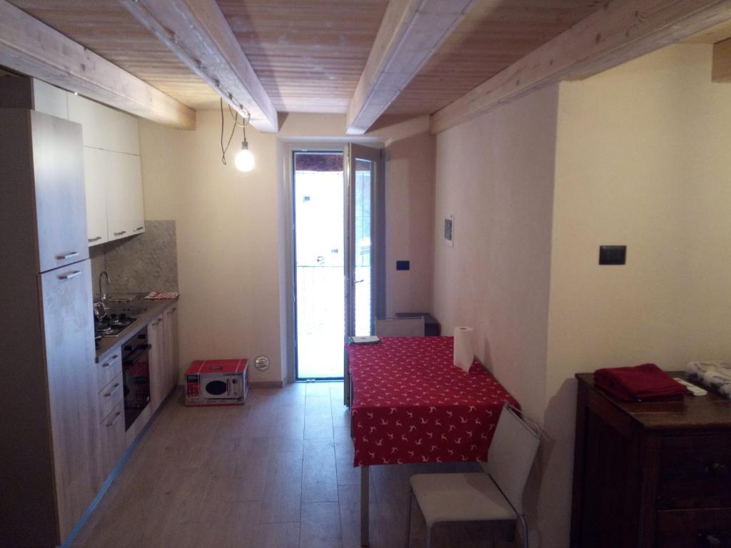 una pequeña cocina con una mesa roja y una habitación en Casa DiBiLeo, en Demonte