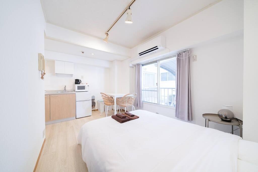 a white bedroom with a large bed and a kitchen at Takadanobaba Address102 in Tokyo
