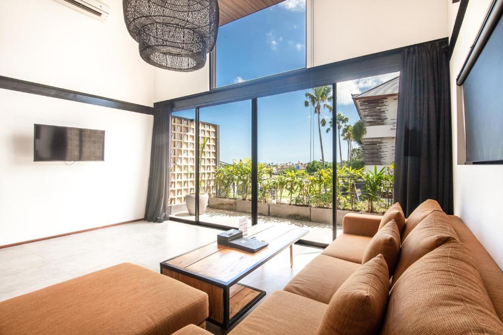 a living room with a couch and a large window at Lofty Nyc Vibes 200m To Canggu Beach in Canggu