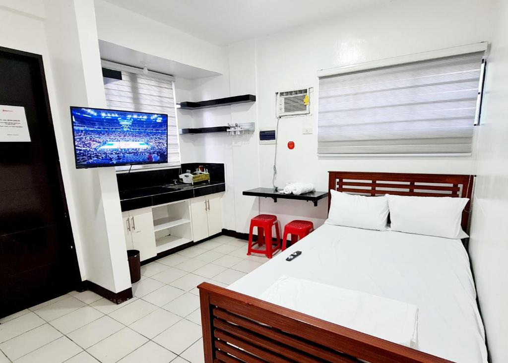 Schlafzimmer mit einem Bett und einem Flachbild-TV in der Unterkunft Dasma Lofts Hotel near Dela Salle Dasma in Dasmariñas