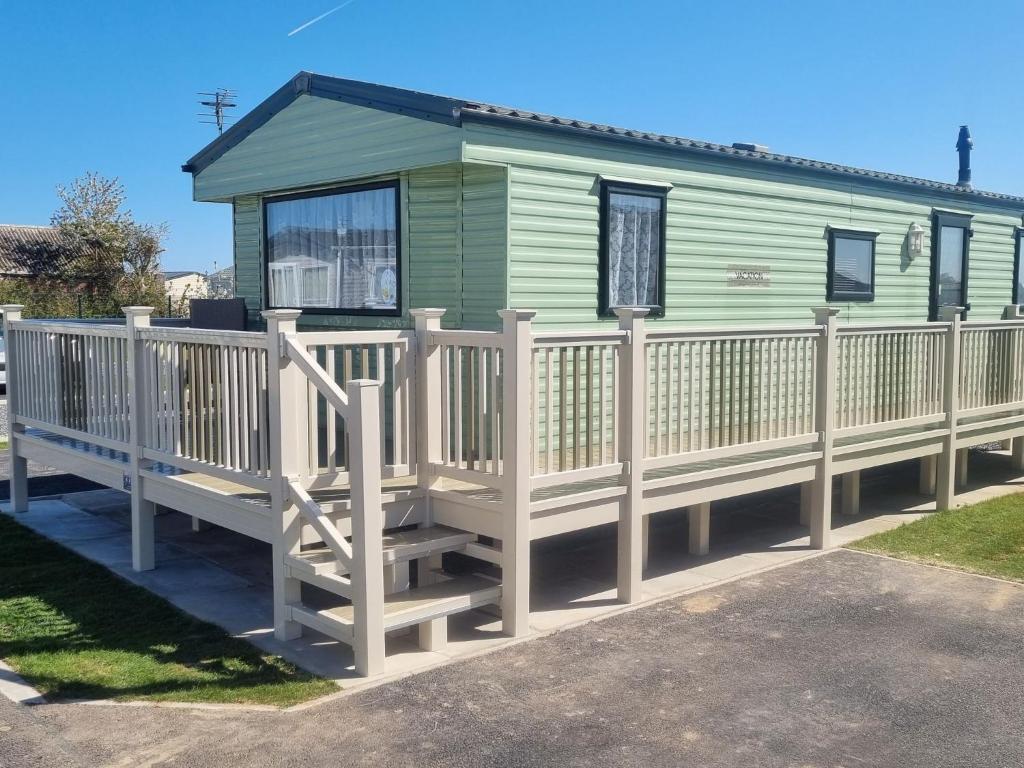 a green mobile home with a wooden deck at Pg151 PALM GROVE THE GOLDEN PALM CHAPEL ST LEONARDS in Chapel Saint Leonards