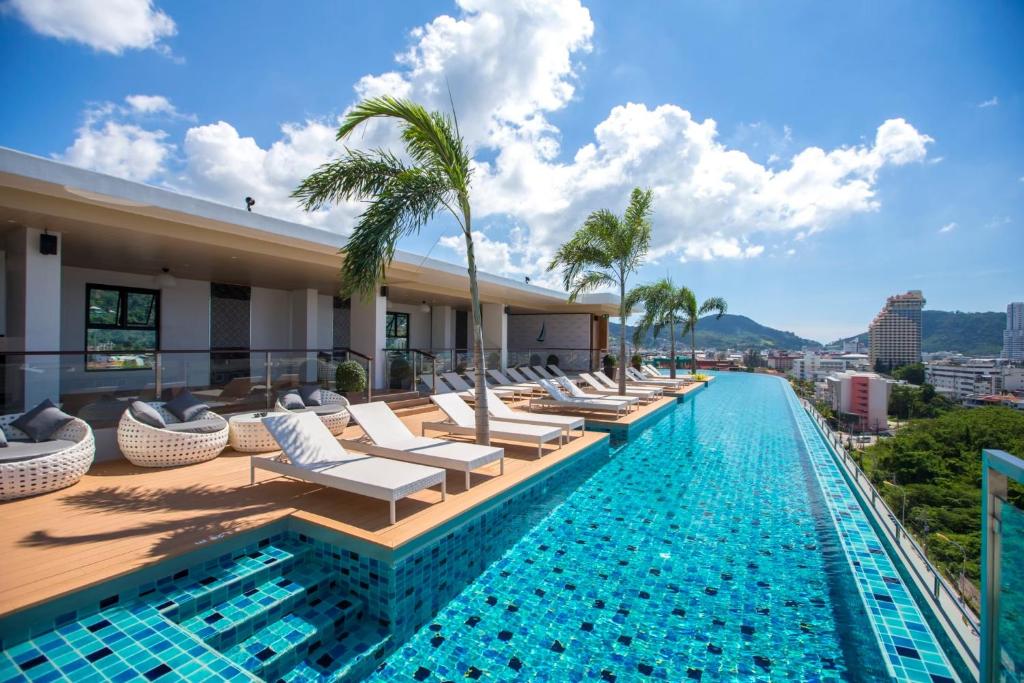 een zwembad van het hotel met ligstoelen en palmbomen bij The Marina Phuket Hotel in Patong Beach
