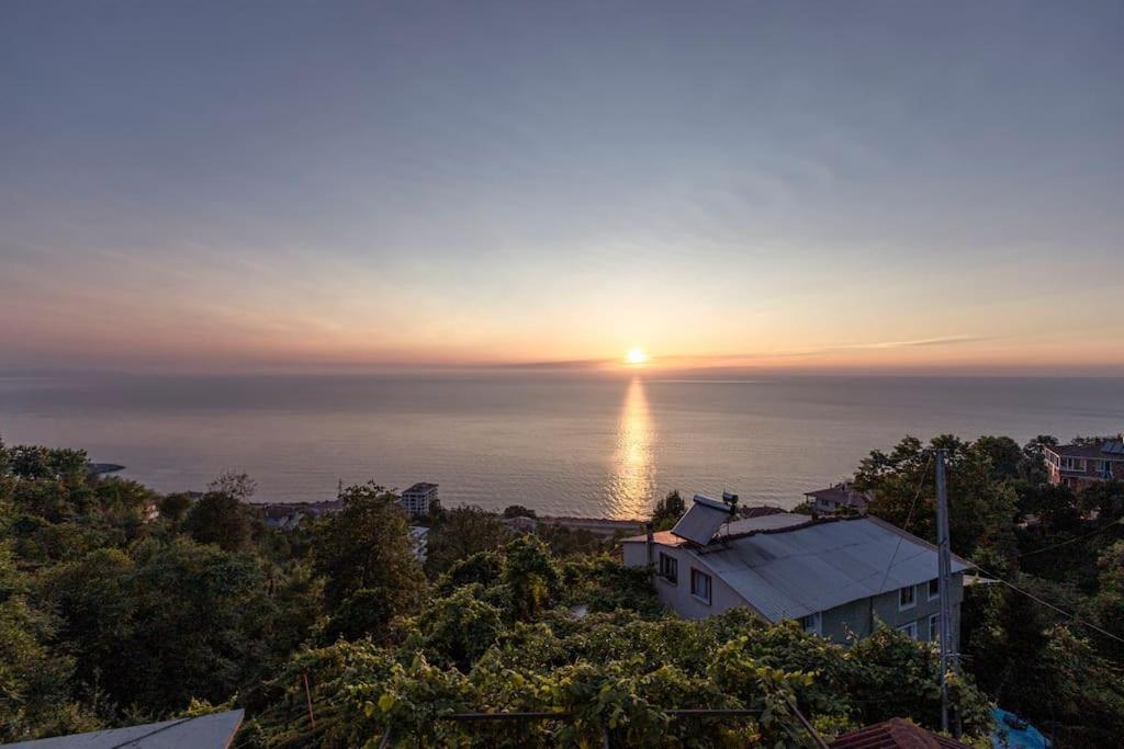um pôr-do-sol sobre o oceano com uma casa em Doğanın İçindeki Yeriniz em Rize