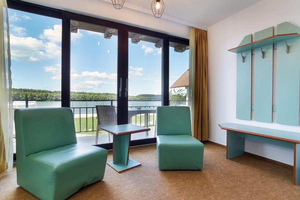 una sala de espera con 2 sillas, una mesa y grandes ventanas en Amore Resort, en Carasuhatul-de-Sus