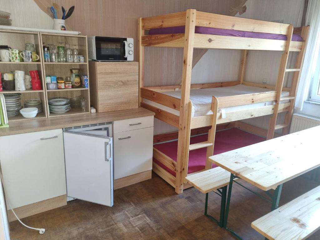 a room with a bunk bed and a desk and a kitchen at Bauernhof Gästezimmer Etagenbetten Gemeinschaftsbad in Hausbreitenbach