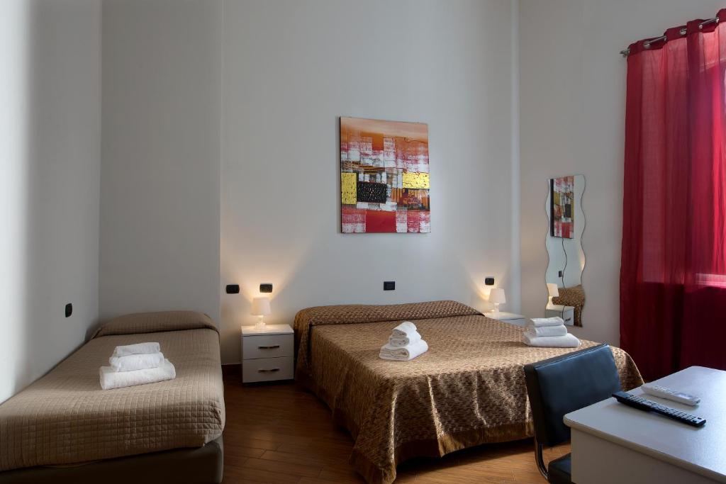 um quarto com 2 camas e uma secretária com uma cadeira em Hotel Diamond em Nápoles