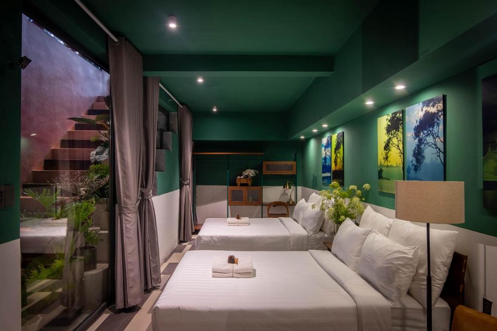 Cette chambre comprend 2 lits et un mur vert. dans l'établissement The Note Dalat, à Đà Lạt