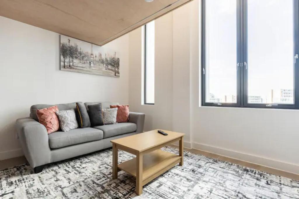 ein Wohnzimmer mit einem Sofa und einem Tisch in der Unterkunft Two Bedrooms Exquisite En-Suite Apartment Deansgate in Manchester