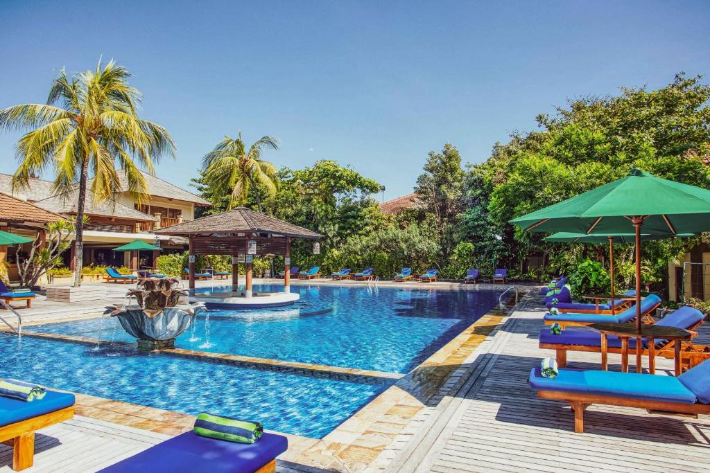 a pool at a resort with chairs and umbrellas at Risata Bali Resort & Spa in Kuta