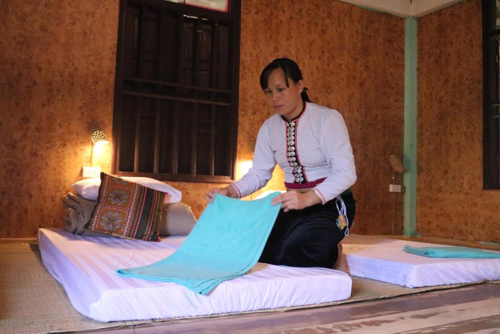 une femme assise sur deux lits dans l'établissement Homestay in Da Bia - Community Based Tourism, à Hòa Bình