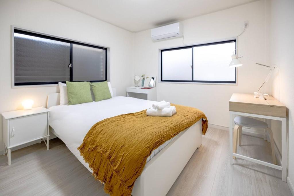 1 Schlafzimmer mit einem großen weißen Bett und 2 Fenstern in der Unterkunft 川口ハウスOsaka 3bedroom House FREE Parking in Osaka