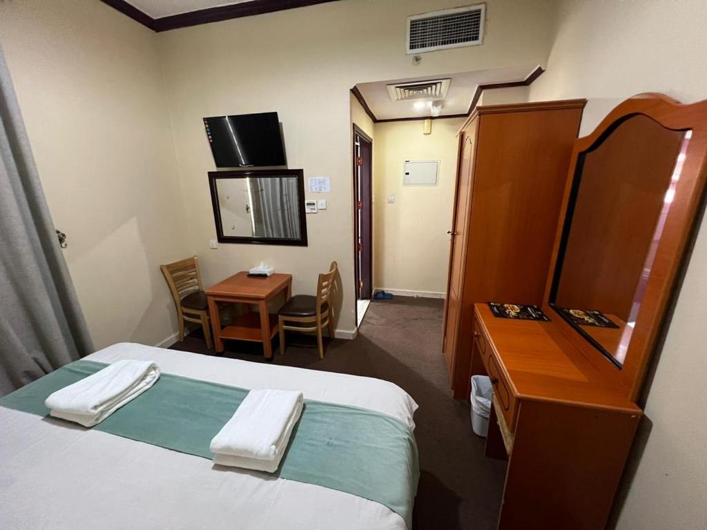 a hotel room with a bed and a desk and a mirror at Al Jazeerah Hotel in Sharjah