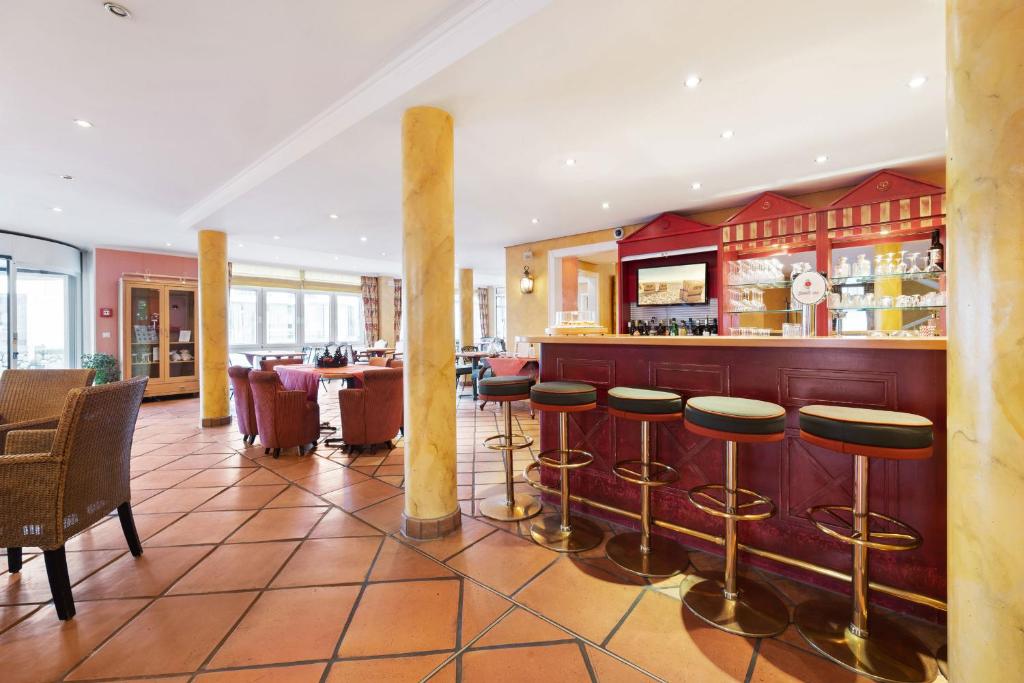 a restaurant with a bar with stools at Strandhotel Sylt Westerland in Westerland