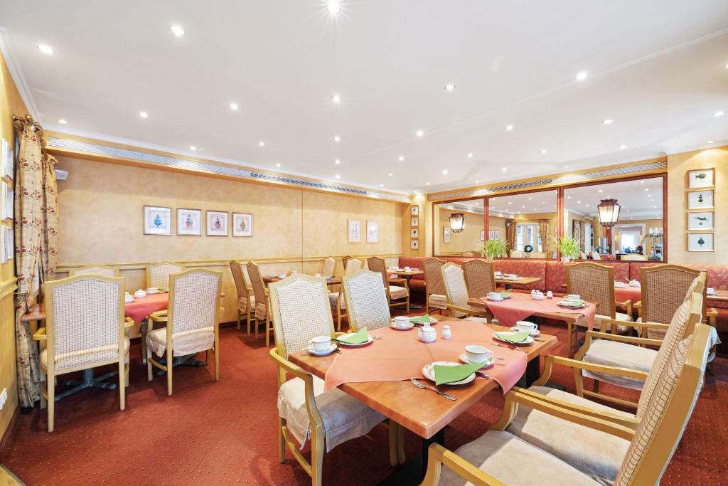 a restaurant with tables and chairs in a room at Strandhotel Sylt Westerland in Westerland