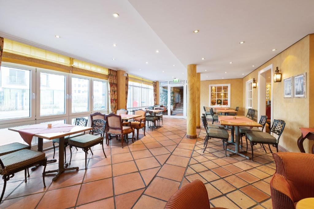a restaurant with tables and chairs and windows at Strandhotel Sylt Westerland in Westerland