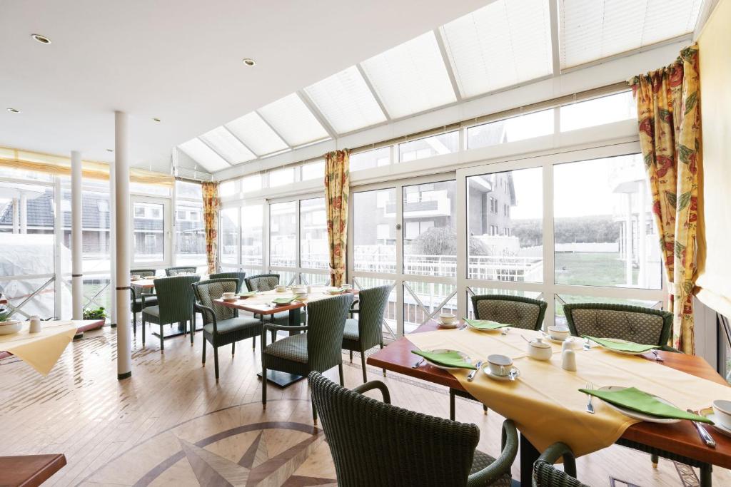 a restaurant with tables and chairs and a large window at Strandhotel Sylt Westerland in Westerland