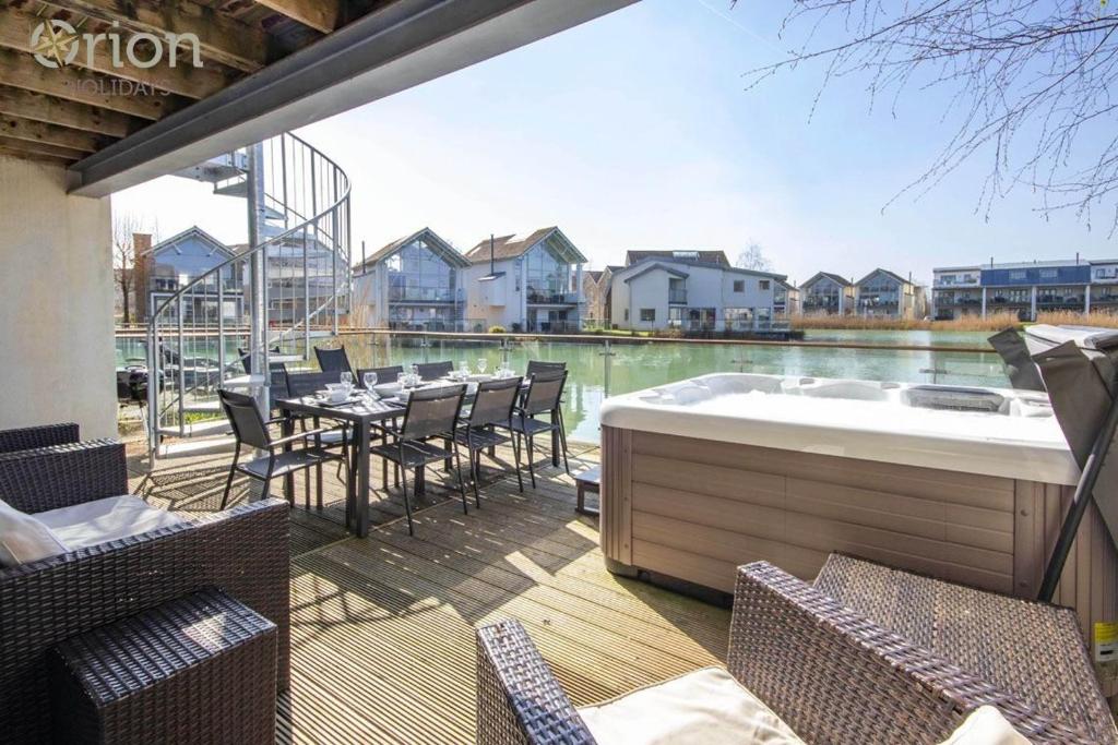 a patio with a hot tub and tables and chairs at Howells Mere 26, Swans Down - P in Somerford Keynes