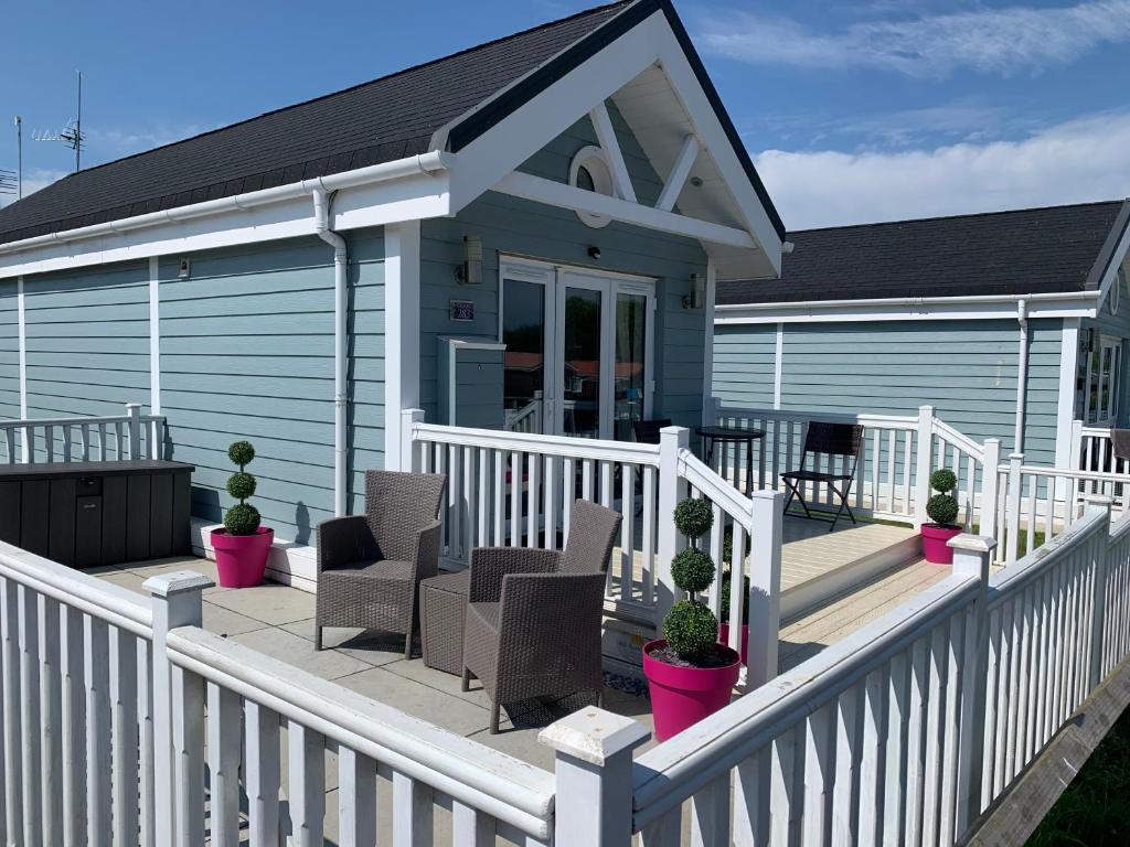 a house with a white deck with chairs and plants at Chalet 283 in Bridlington
