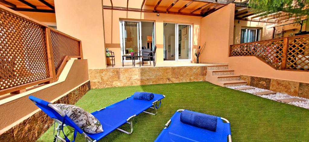 d'un balcon avec 2 chaises bleues et de la pelouse. dans l'établissement Ferienhaus SUN & OCEAN in Gran Tarajal, à Gran Tarajal