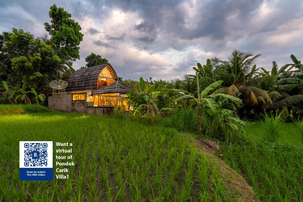 a house in a field with a sign in front of it at Pondok Carik Villa Manggis in Manggis