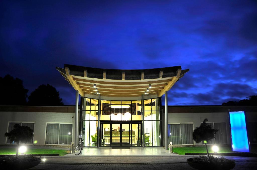 un edificio con una gran puerta de cristal por la noche en Fletcher Hotel Restaurant Doorwerth - Arnhem en Doorwerth