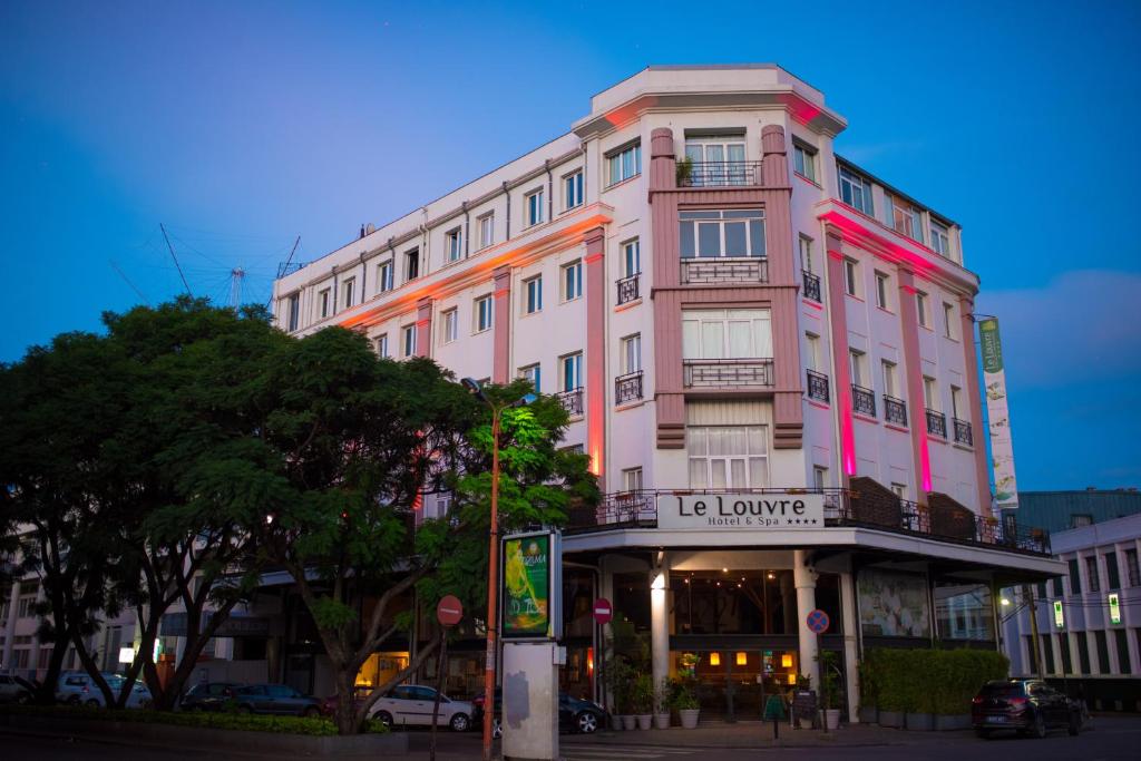 un grand bâtiment rose au coin d'une rue dans l'établissement Le Louvre Hotel & Spa, à Antananarivo