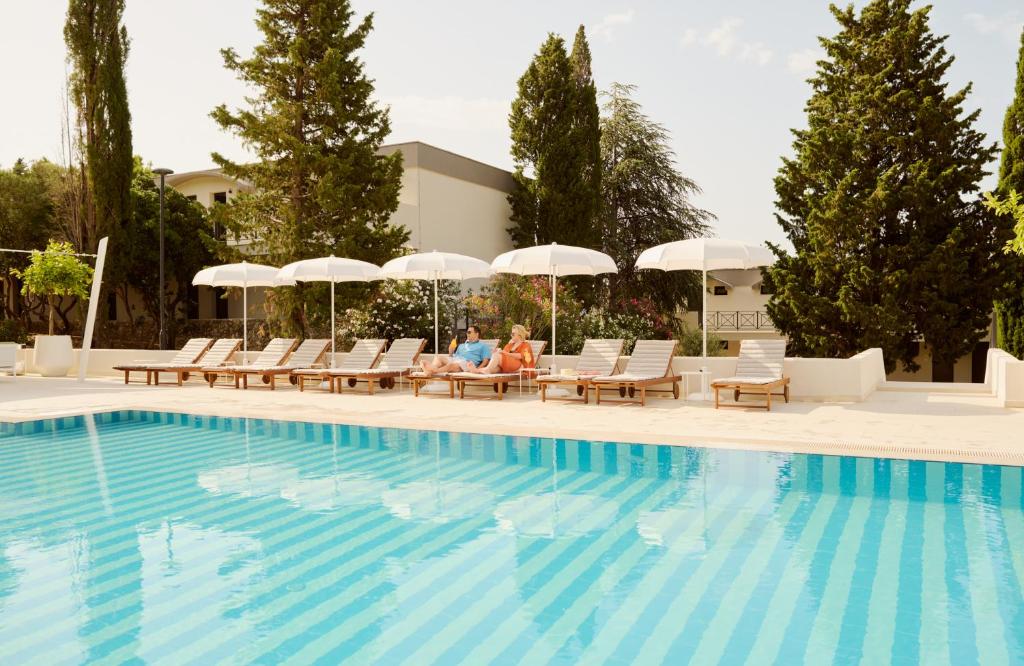 a couple sitting in chairs next to a swimming pool at Bluesun Holiday Village Bonaca - Full Board Plus in Bol