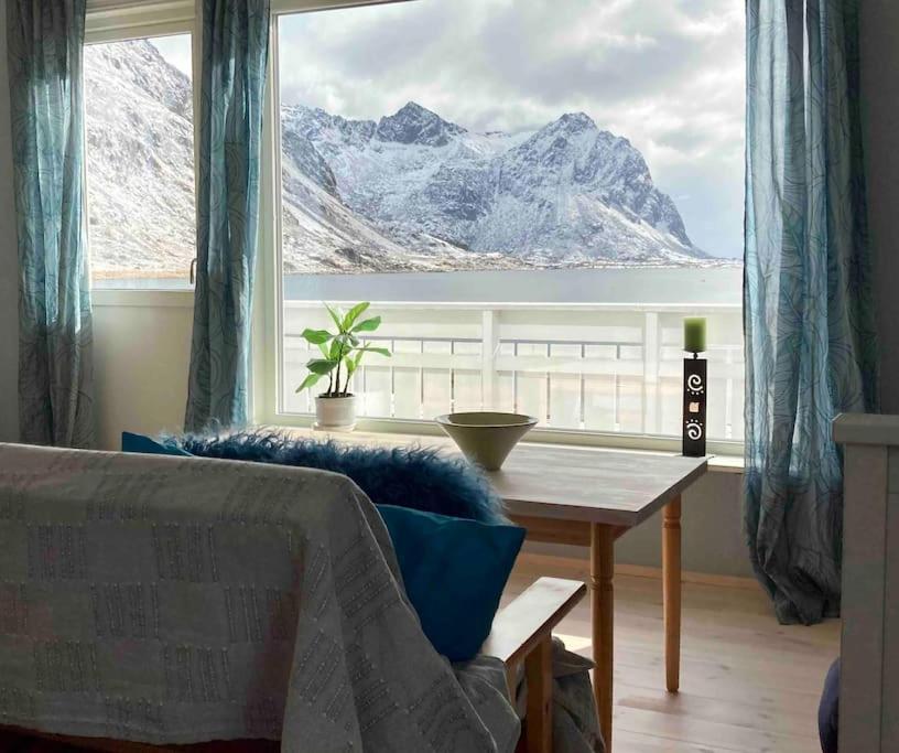 a living room with a table and a large window at Charming house in fjord Lofoten 