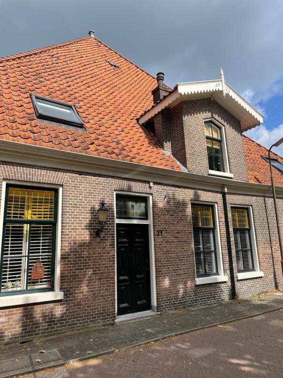 a brick house with an orange roof and a black door at Tante roosje in Enkhuizen