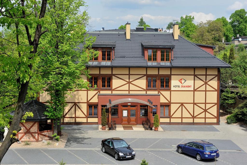 ein großes Gebäude mit zwei Autos auf einem Parkplatz in der Unterkunft Hotel Diament Bella Notte Katowice - Chorzów in Chorzów