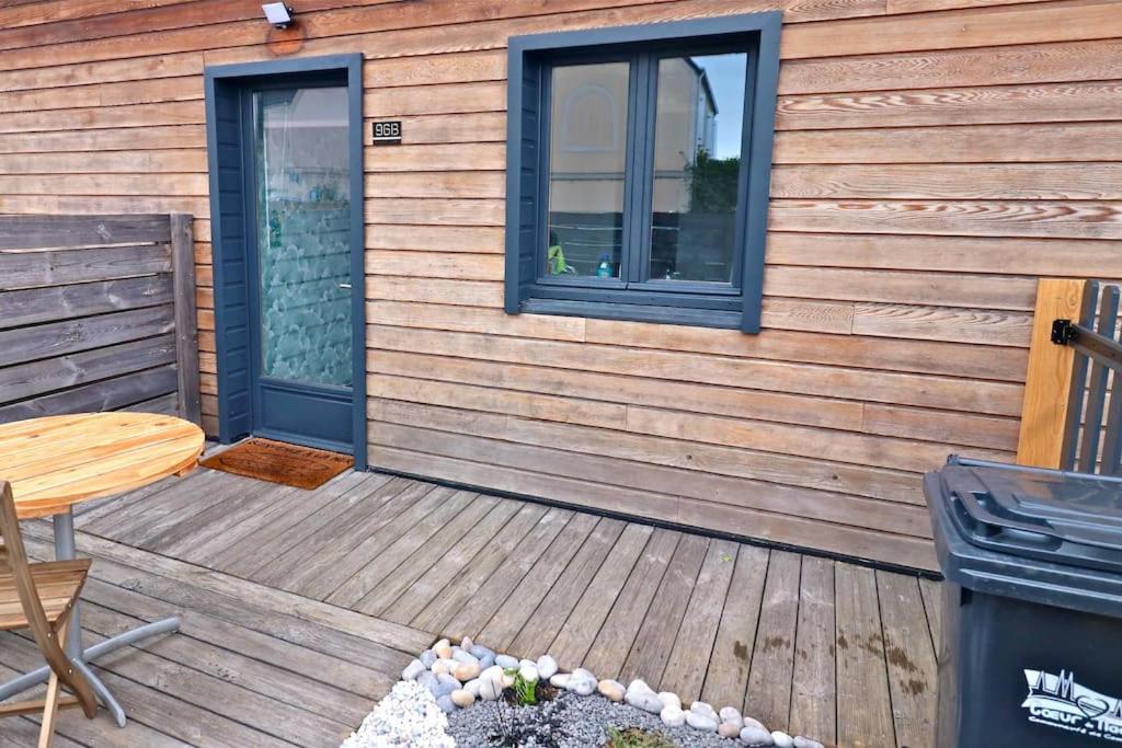 una terraza de madera con mesa y ventana en Maison avec terrasses à 300m de la mer Juno Beach, en Bernières-sur-Mer