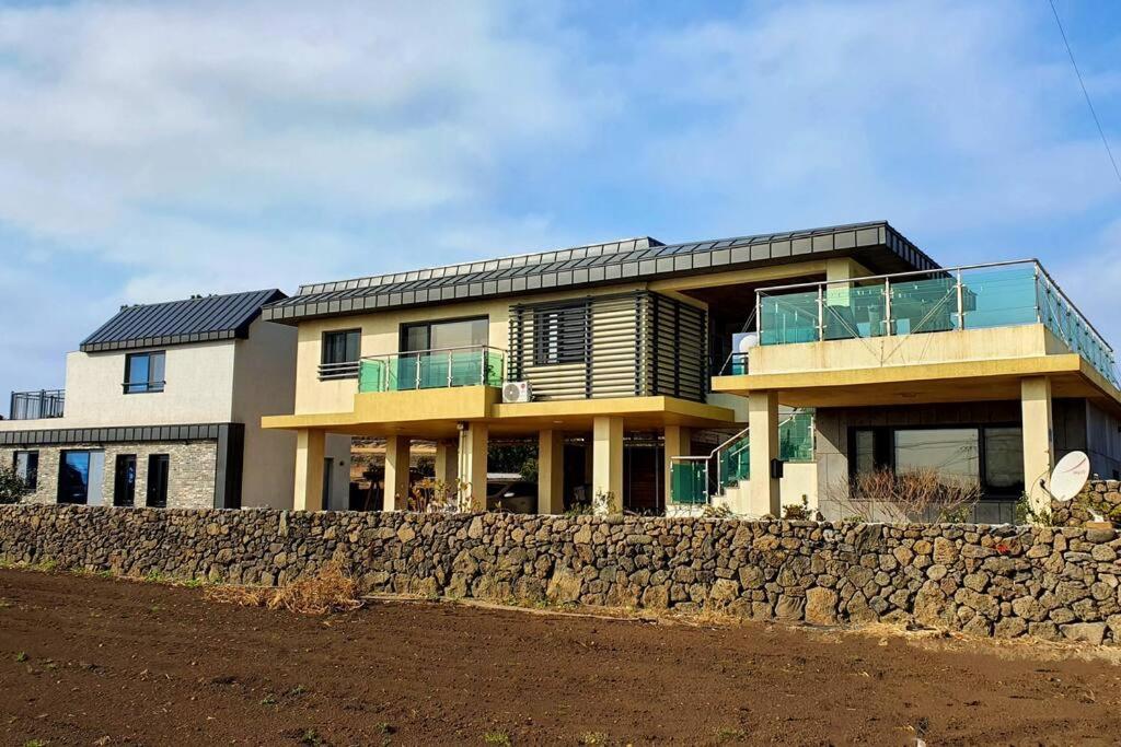 a large house with a stone wall at Mirine Jeju in Jeju