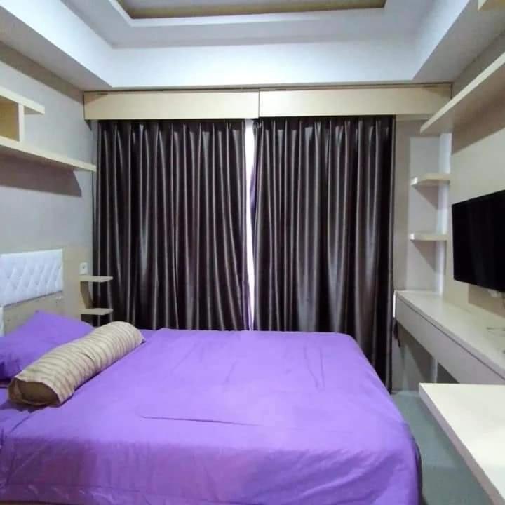 a bedroom with a purple bed and a window at Andalemi Home Stay in Ciwidey