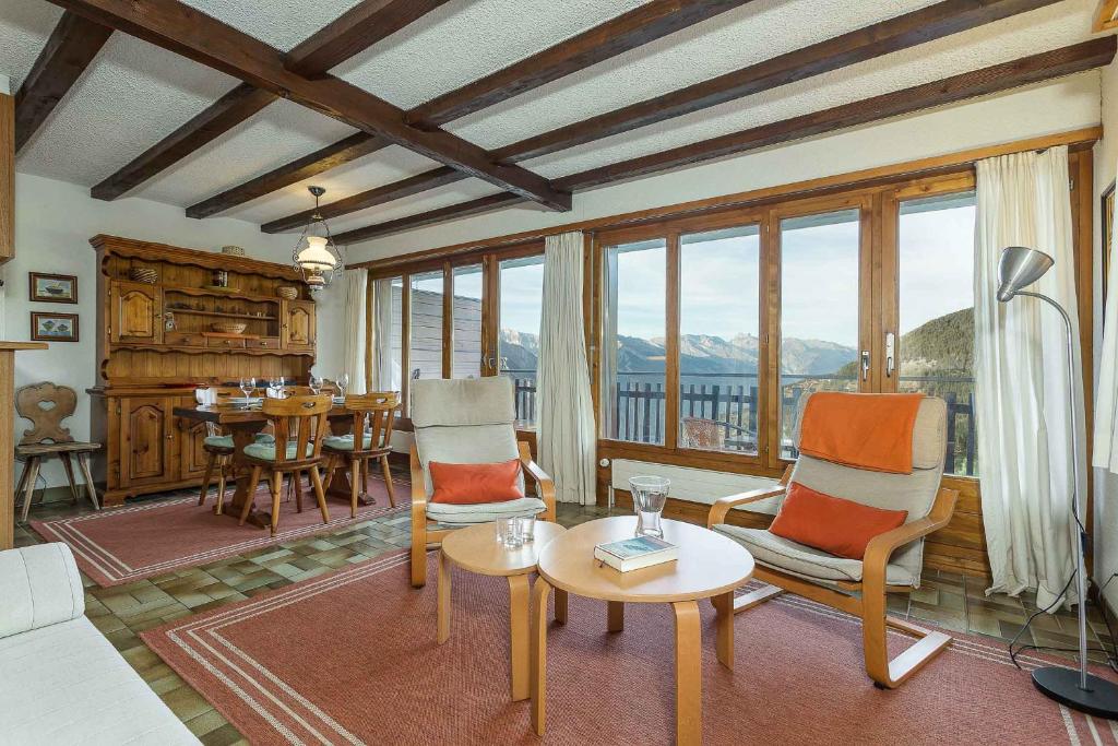 a living room with chairs and a table and some windows at Appartement Arolles 704 in La Tzoumaz