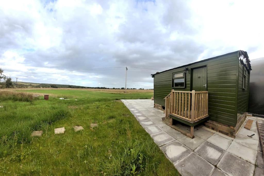 a green trailer with a porch in a field at Runaway Northumberland in Morpeth