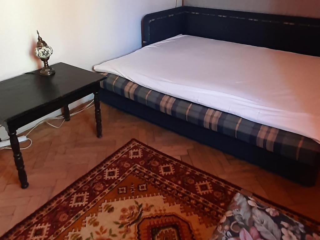 Schlafzimmer mit einem Bett, einem Tisch und einem Teppich in der Unterkunft Эконом вариант - квартира в центре из первых рук in Tschernihiw