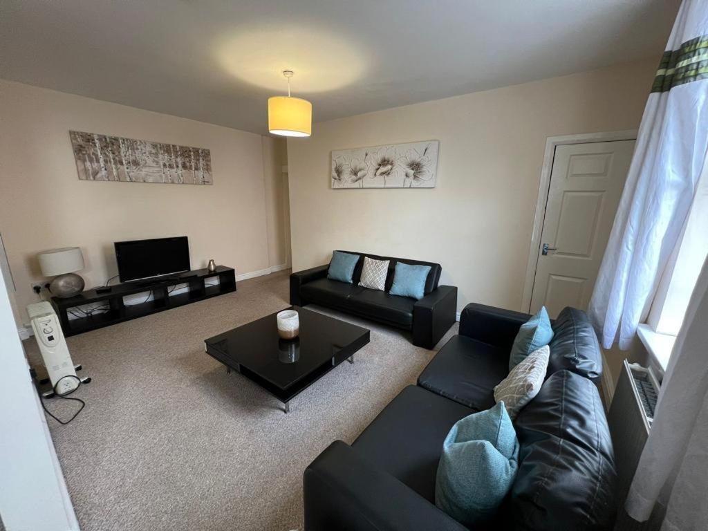 uma sala de estar com um sofá preto e uma mesa em Alexander Apartments South Shields 2 em South Shields