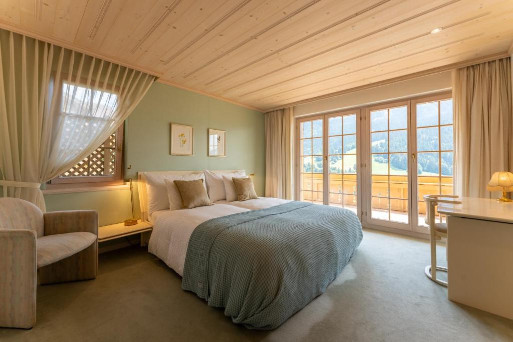 Schlafzimmer mit einem Bett, einem Stuhl und Fenstern in der Unterkunft Chalet Solidage in Rougemont