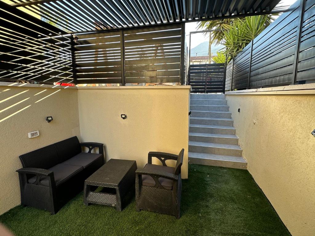 a balcony with a couch and chairs and stairs at צימר על הנחל in Qiryat Shemona