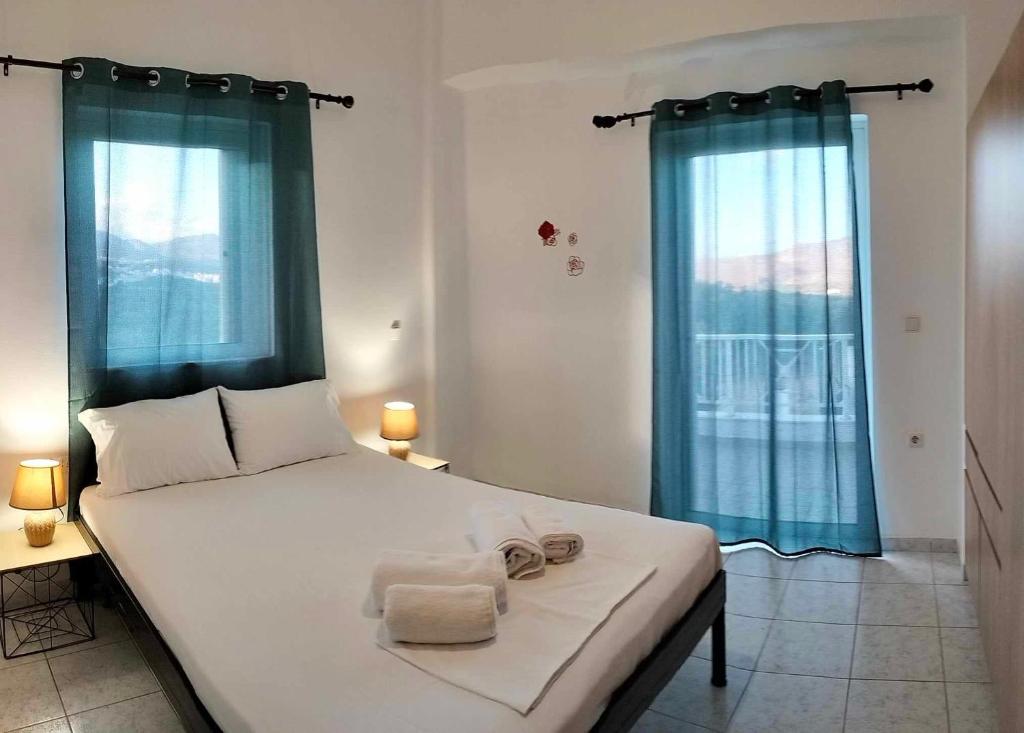 sypialnia z dużym białym łóżkiem z niebieskimi zasłonami w obiekcie Villa Helen's Olive Garden w mieście Xerokampos