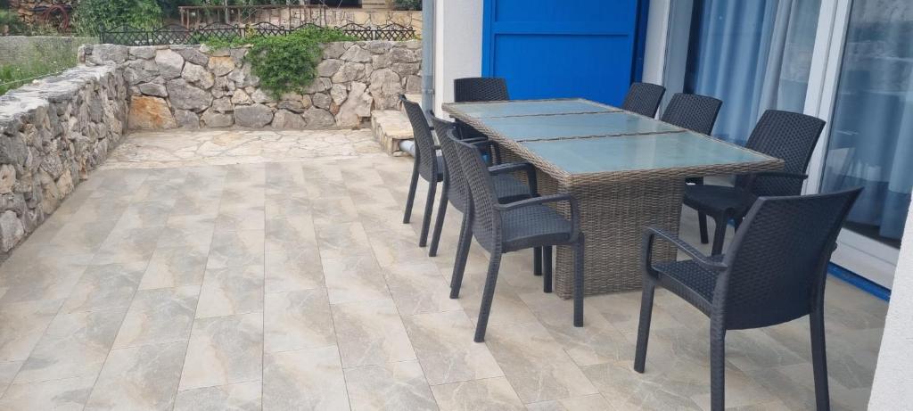 a patio with a table and chairs and a stone wall at Villa Karla B&B in Veli Iž