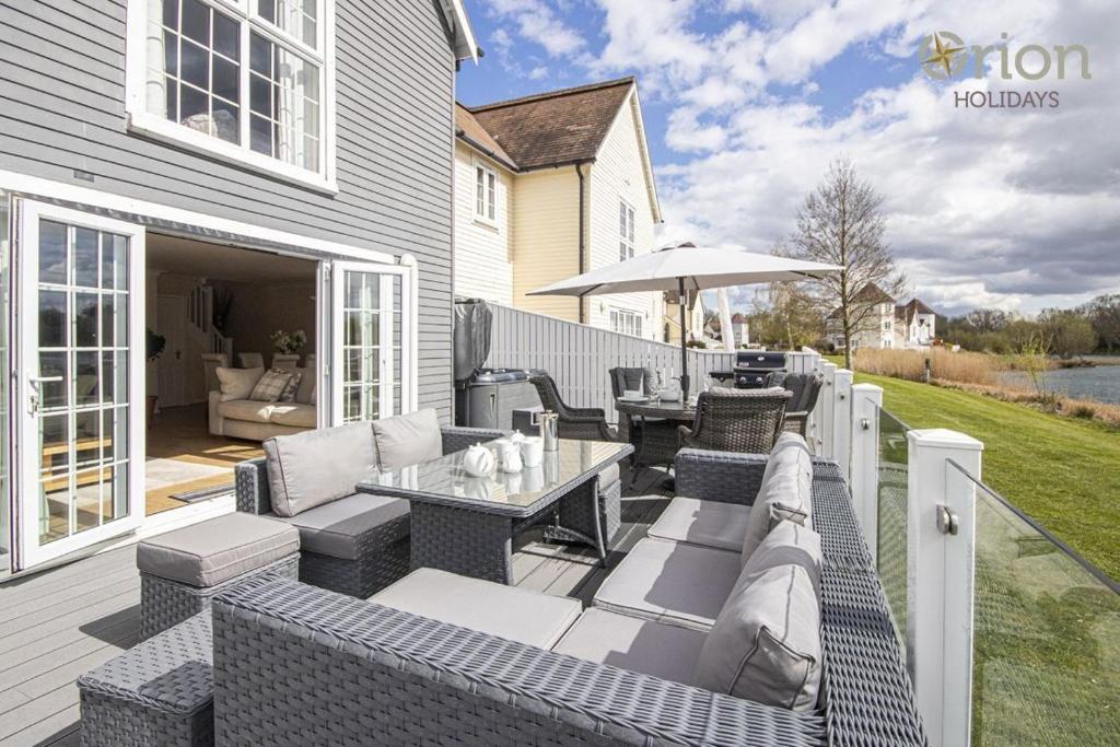 a patio with couches and a table and an umbrella at Windrush Lake 66, Sun Kissed Lodge in South Cerney