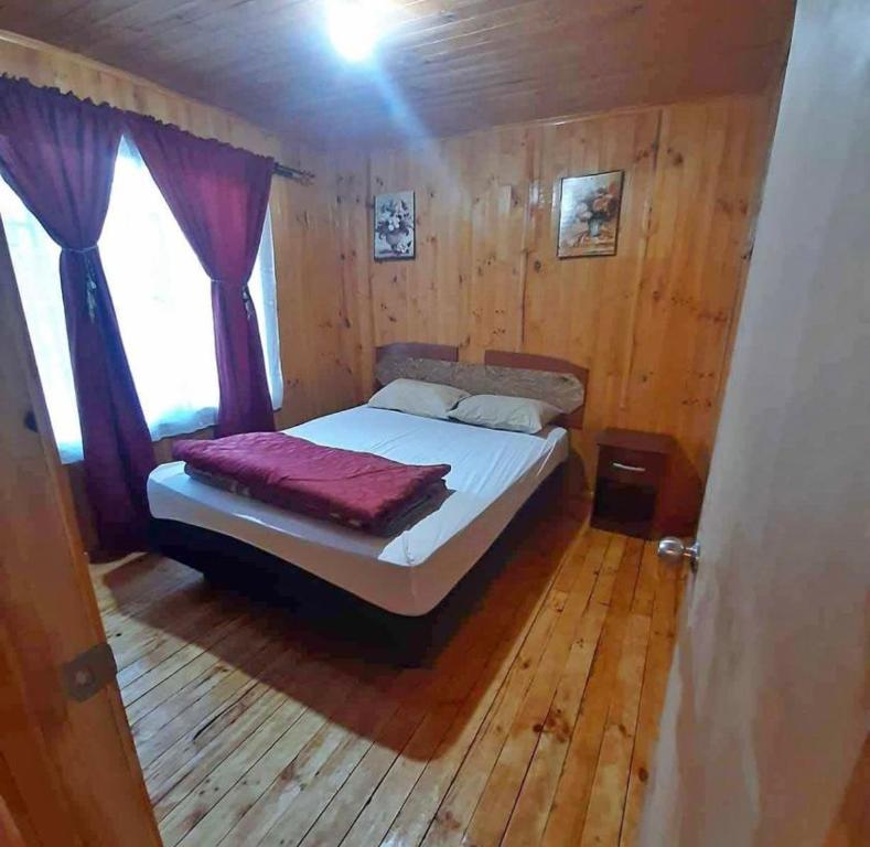 um quarto com uma cama num quarto de madeira em Cabañas amobladas en salto del laja a 2 minutos del puente salto del laja em El Manzano