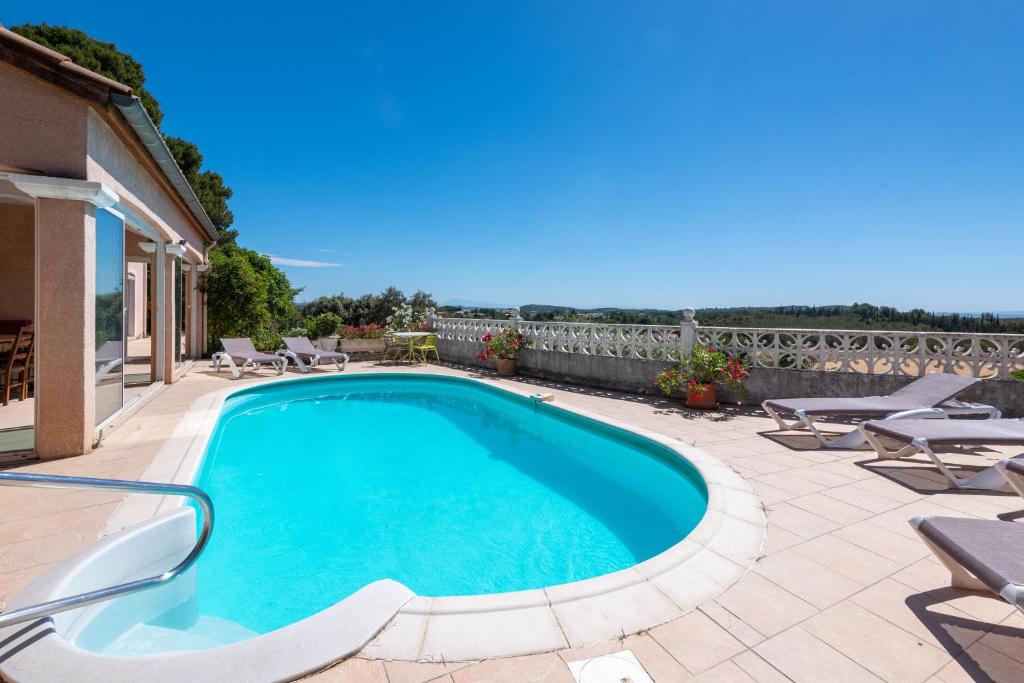 una piscina en un patio con tumbonas en Maison avec piscine et belle vue, en Lédenon